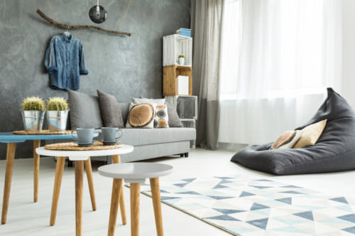 Modern minimalistic and bright living room in shades of cyan with sofa, bean bag chair, three coffee tables, carpet and stillage made of wooden cases